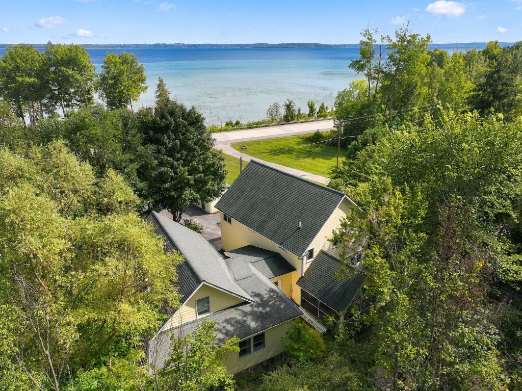 Aerial of a yellow home among trees above the bay